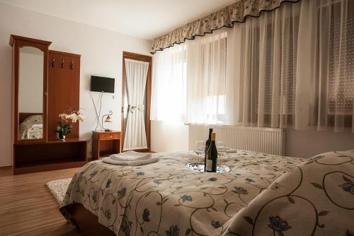 Un dormitorio con una cama con una botella de vino. en Wekler Családi Pincészet és Panzió, en Mecseknádasd