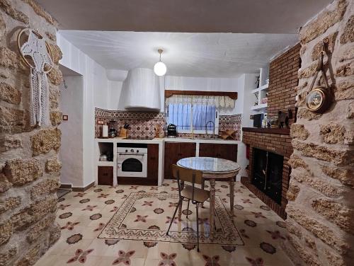 a kitchen with a table and a stone wall at Apartamentos Casa Nino in Montefrío