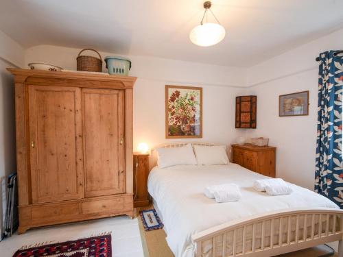 een slaapkamer met een bed en een houten kast bij Naunton Cottage in Lyme Regis