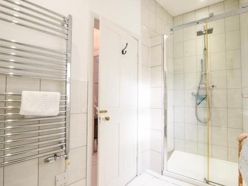 een badkamer met een douche en een glazen deur bij Naunton Cottage in Lyme Regis