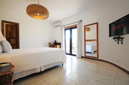 a bedroom with a large white bed and a window at Villa Santa Fé in Búzios