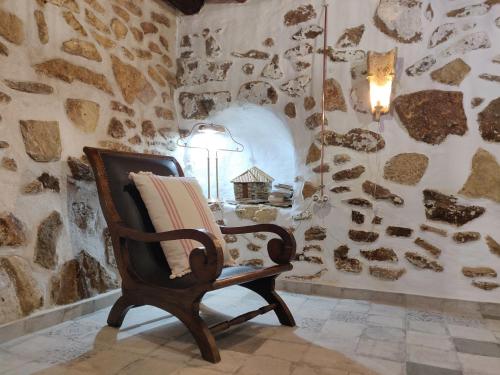 a rocking chair in a room with a stone wall at Apartamentos Casa Nino in Montefrío