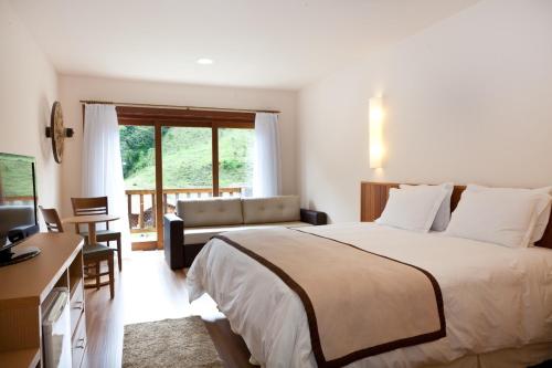a bedroom with a bed and a desk and a window at Fazenda Suica Le Canton in Teresópolis