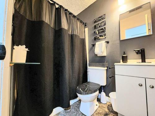ein Bad mit einem schwarzen Duschvorhang und einem WC in der Unterkunft HI-TEK MANOR 2 - Prime Location - 2-75 inch 4K TVs in Charleston