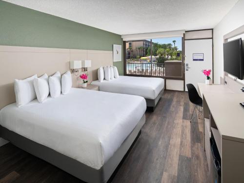 a hotel room with two beds and a flat screen tv at Wyndham I-Drive Avanti Resort & Conference Center in Orlando
