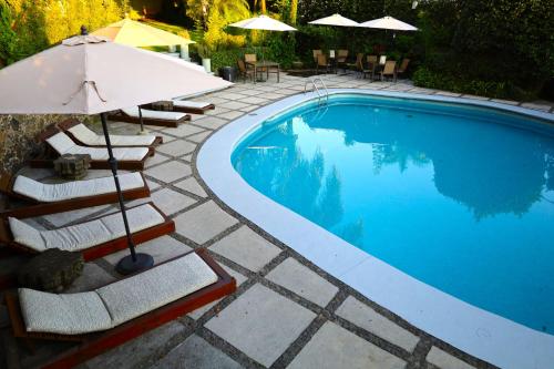 a swimming pool with chairs and an umbrella next to it at Hotel Grand Vista Cuernavaca in Cuernavaca