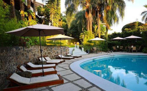 a swimming pool with lounge chairs and umbrellas next to a pool at Hotel Grand Vista Cuernavaca in Cuernavaca