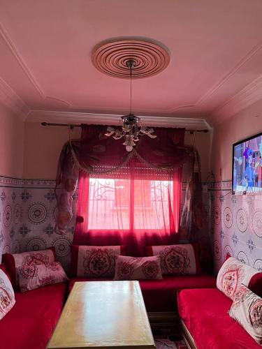 a living room with a red couch and a window at Azrou ifrane in Azrou