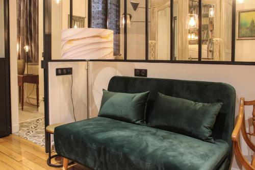 eine grüne Couch in einem Zimmer mit Spiegeln in der Unterkunft Large cozy nest on the outskirts of Paris in Asnières-sur-Seine
