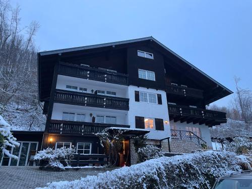 a white and black building with snow on the ground at Pension 's Waldeck in Traunkirchen