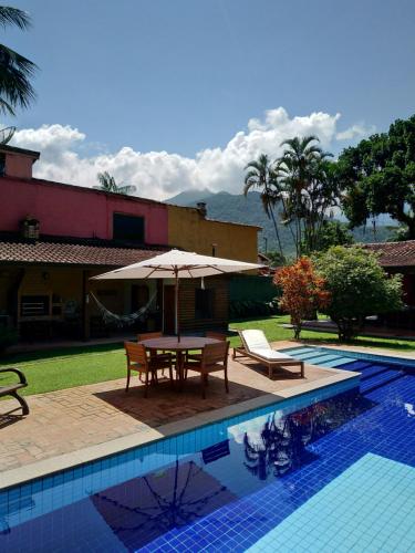 - une table avec un parasol et des chaises à côté de la piscine dans l'établissement Flat Vila Caiçara, à Ilhabela