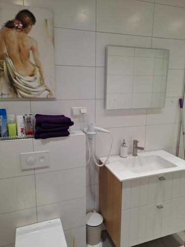 a bathroom with a sink and a painting of a woman at Emajõe Keeltekool Apartment in Tartu