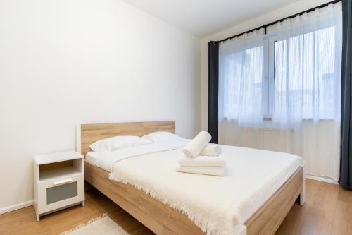 a bedroom with a bed with white sheets and a window at Szurmana Comfort Apartment in Katowice