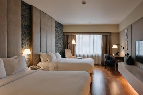 a hotel room with two beds and a desk at Manto Hotel Lima - MGallery Collection in Lima