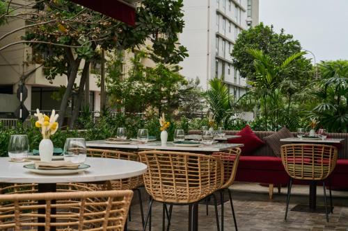 a patio with tables and chairs and a couch at Manto Hotel Lima - MGallery Collection in Lima