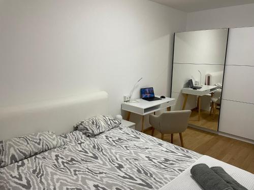 Schlafzimmer mit einem Bett und einem Schreibtisch mit einem Laptop in der Unterkunft City Vibe in Obrenovac