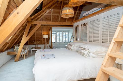 ein Schlafzimmer mit einem großen weißen Bett im Dachgeschoss in der Unterkunft Zilverzoen Slapen in Elburg