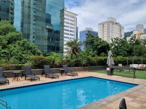 uma piscina com cadeiras, mesas e edifícios em Condomínio Max Savassi Superior apto 1502 em Belo Horizonte