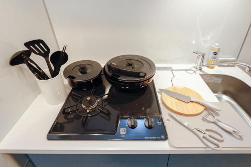 - une cuisinière avec 2 casseroles et des poêles sur un comptoir dans l'établissement Seaside Tamachi - Vacation STAY 15740, à Tokyo