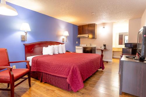 a hotel room with a red bed and a kitchen at Motel Puyallup in Puyallup