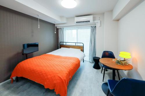 ein Schlafzimmer mit einem orangenen Bett und einem Tisch in der Unterkunft Seaside Tamachi - Vacation STAY 15580 in Tokio
