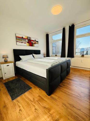 a large bed in a room with two windows at Schicke Wohnung im grünen Hinterhof in Schwerin