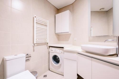 a white bathroom with a washing machine and a sink at Residence with Urban View 5 min to Optimum Mall in Istanbul