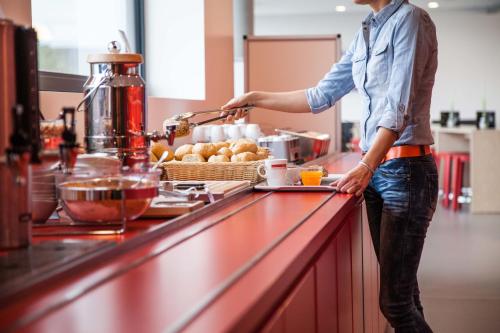 a man standing at a kitchen counter preparing food at havenhostel Cuxhaven in Cuxhaven