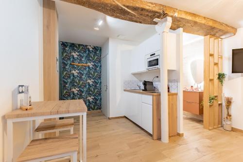 a small kitchen with a wooden table and a stove at L'Eden Zen - Suite Jacuzzi, parking, clim, Netflix in Béziers