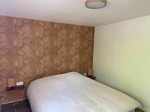 - une chambre avec un lit et un mur en bois dans l'établissement Gîte Vogelau, à Schiltigheim