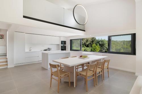 a white kitchen with a white table and chairs at Myrtia - Luxury Hidden Gem in Corfu Town
