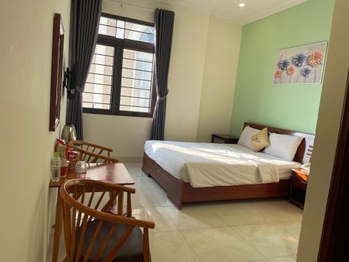a bedroom with a bed and a table and a window at Khách sạn Khải Hoàn in Plei Brel (2)