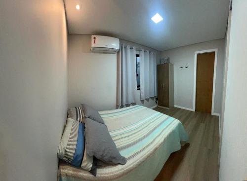 a small bedroom with a bed and a window at CASA DE PRAIA -Palmas Governador Celso Ramos, Sc in Governador Celso Ramos