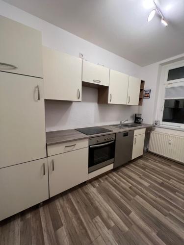 een lege keuken met witte kasten en een houten vloer bij Pretty Home Chemnitz Süd in Chemnitz