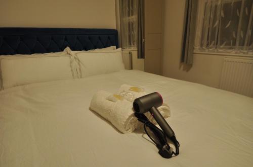 a black flashlight laying on a bed with a towel at Harlesden House in London