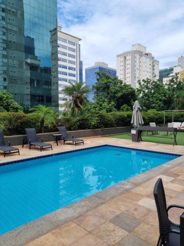 einen Pool mit Stühlen und eine Skyline der Stadt in der Unterkunft Condomínio Max Savassi Superior apto 1302 in Belo Horizonte