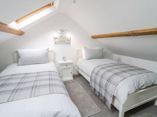 two beds in a room with white walls and wooden beams at 23 Chapel Street in Conwy