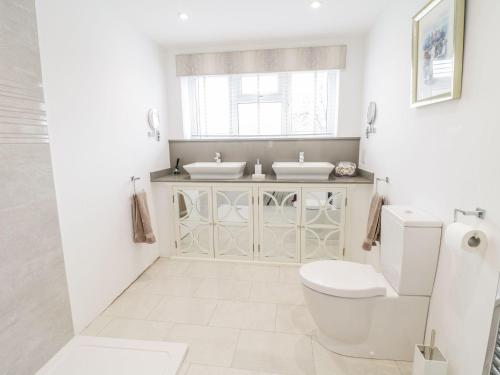 a white bathroom with two sinks and a toilet at 23 Chapel Street in Conwy