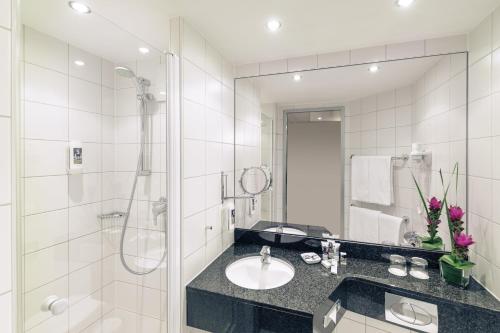a bathroom with a sink and a shower and a mirror at Mercure Hotel Mannheim am Rathaus in Mannheim