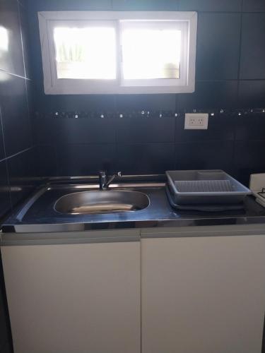 eine Küchentheke mit Spüle und Fenster in der Unterkunft El Departamento de Oscar in Villa María