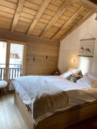 une chambre avec un grand lit avec un plafond en bois dans l'établissement AURON Centre Station - Superbe appartement chalet au pied des pistes, à Saint-Étienne-de-Tinée