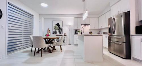 una cucina con tavolo e frigorifero in acciaio inossidabile di Brand New! Modern Luxury Retreat! a Barrie