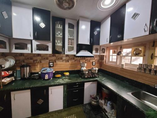 eine Küche mit schwarzen und weißen Schränken und einem Waschbecken in der Unterkunft OYO Home Aalim Homestay 