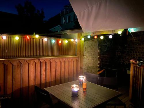 a wooden table with candles on a fence with lights at Yport, maison de pêcheur avec jolie terrasse. in Yport