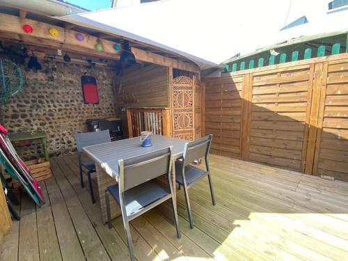 a wooden patio with a table and chairs on a deck at Yport, maison de pêcheur avec jolie terrasse. in Yport