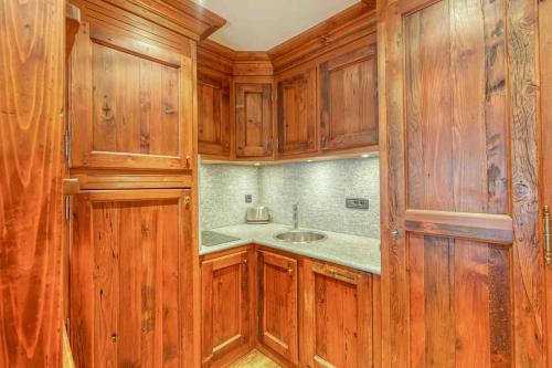 une cuisine avec des armoires en bois et un évier dans l'établissement Chamonix centre, « Lucille »,balcon, vue imprenable et parking, à Chamonix-Mont-Blanc