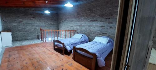duas camas num quarto com uma parede de tijolos em De leon em Rosário