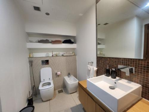 a bathroom with a white toilet and a sink at Sea View 1BR Al Raha Beach in Abu Dhabi