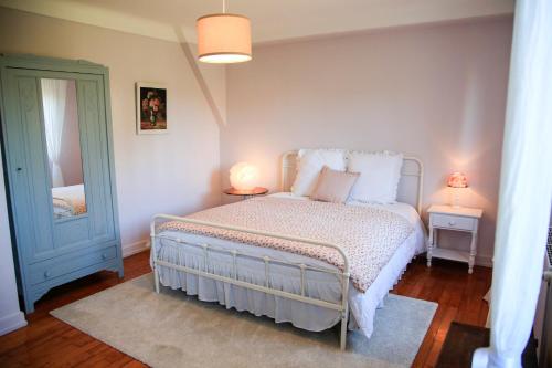 a bedroom with a bed with two lamps and a mirror at Villa Camélias, appartement avec jardin partagé et parking in Mittelwihr
