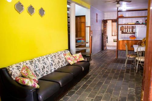 ein schwarzes Sofa in einem Zimmer mit gelber Wand in der Unterkunft Casa Pedra & Mar - Paraiso na Praia de Caieiras in Guaratuba